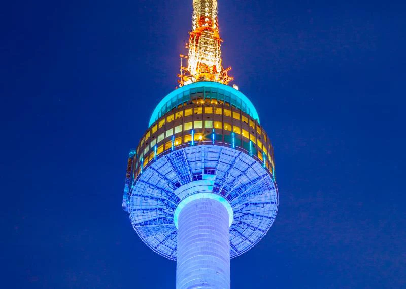 N Seoul Tower illuminated blue and gold against the deep evening sky