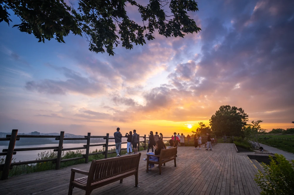 Visitors watching a vivid sunset from the wooden viewpoint at Haneul Park in Seoul
