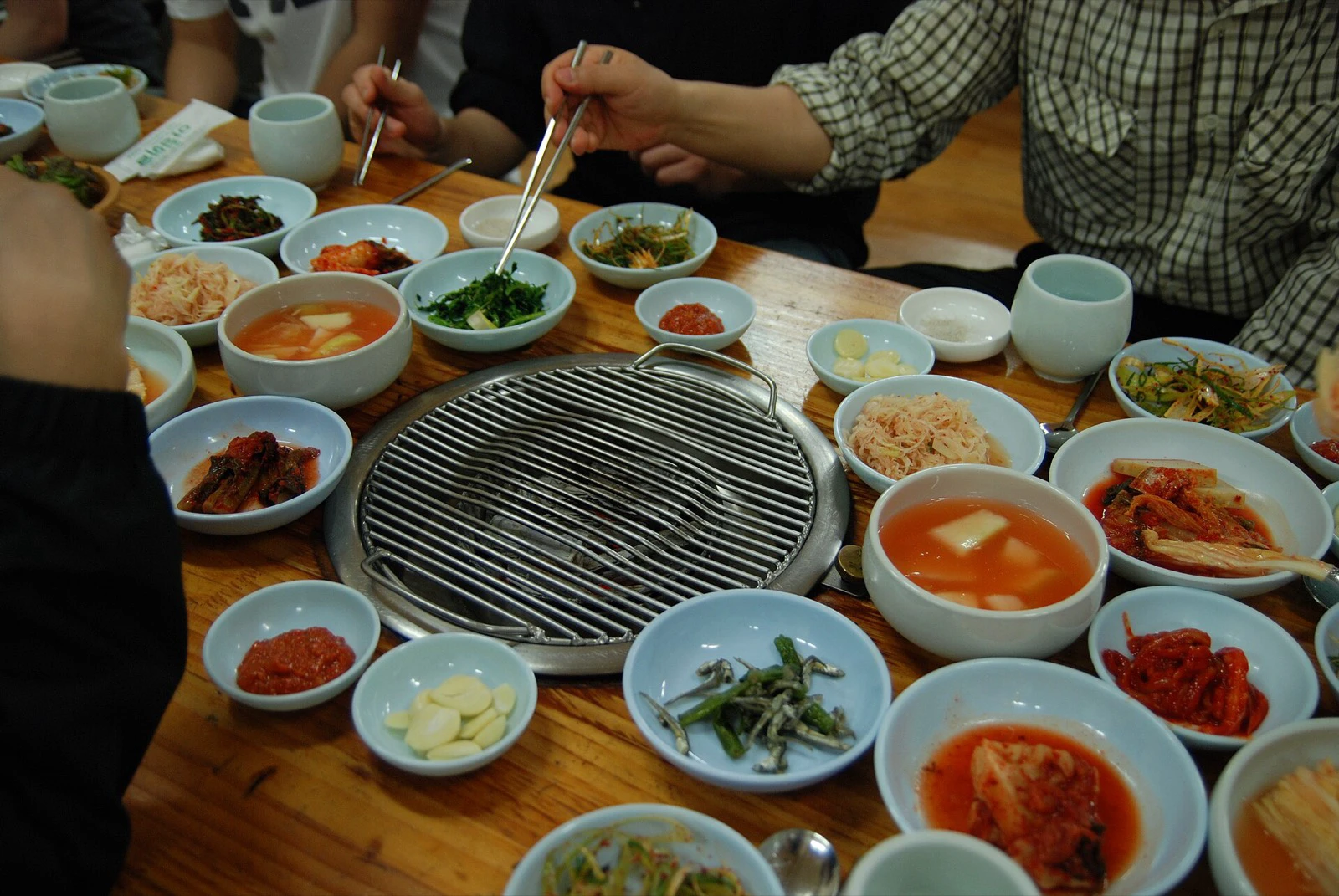 Built-in Korean barbecue grill surrounded by bowls of banchan on a shared table