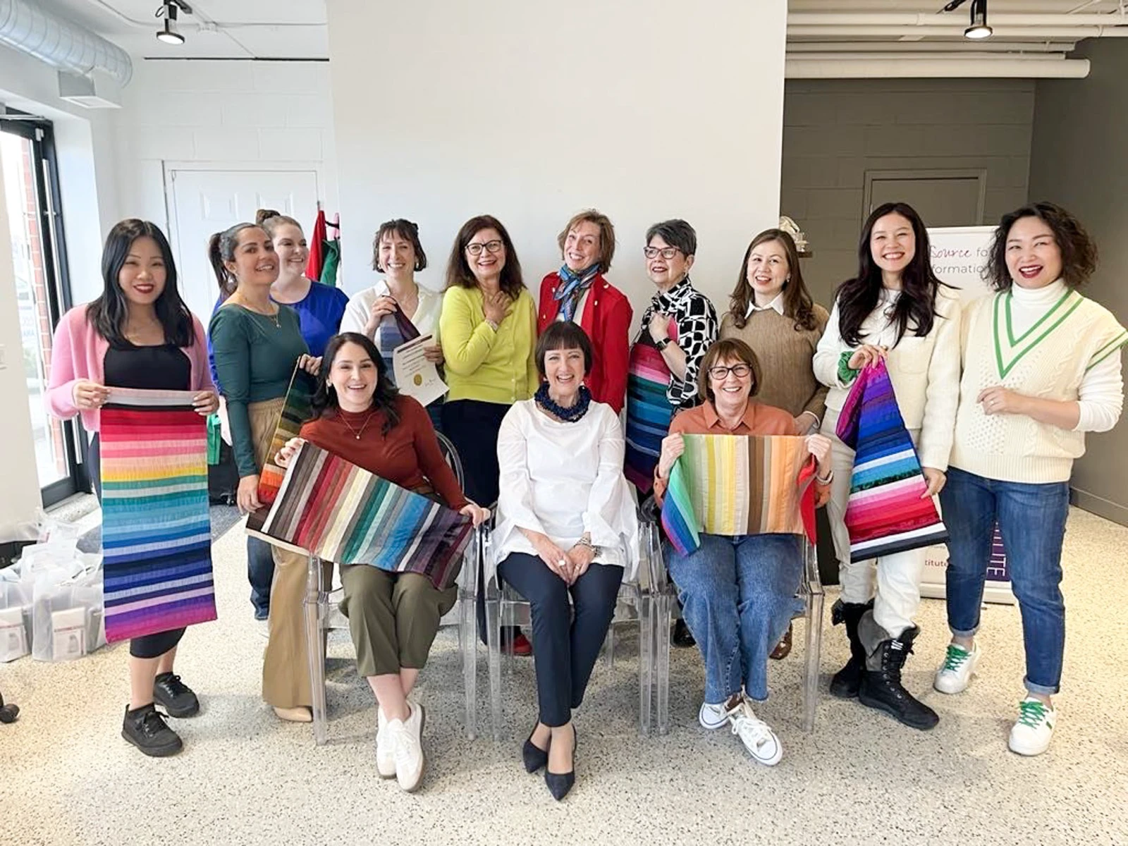 Color analysis trainees holding several fabric palette sets during a class