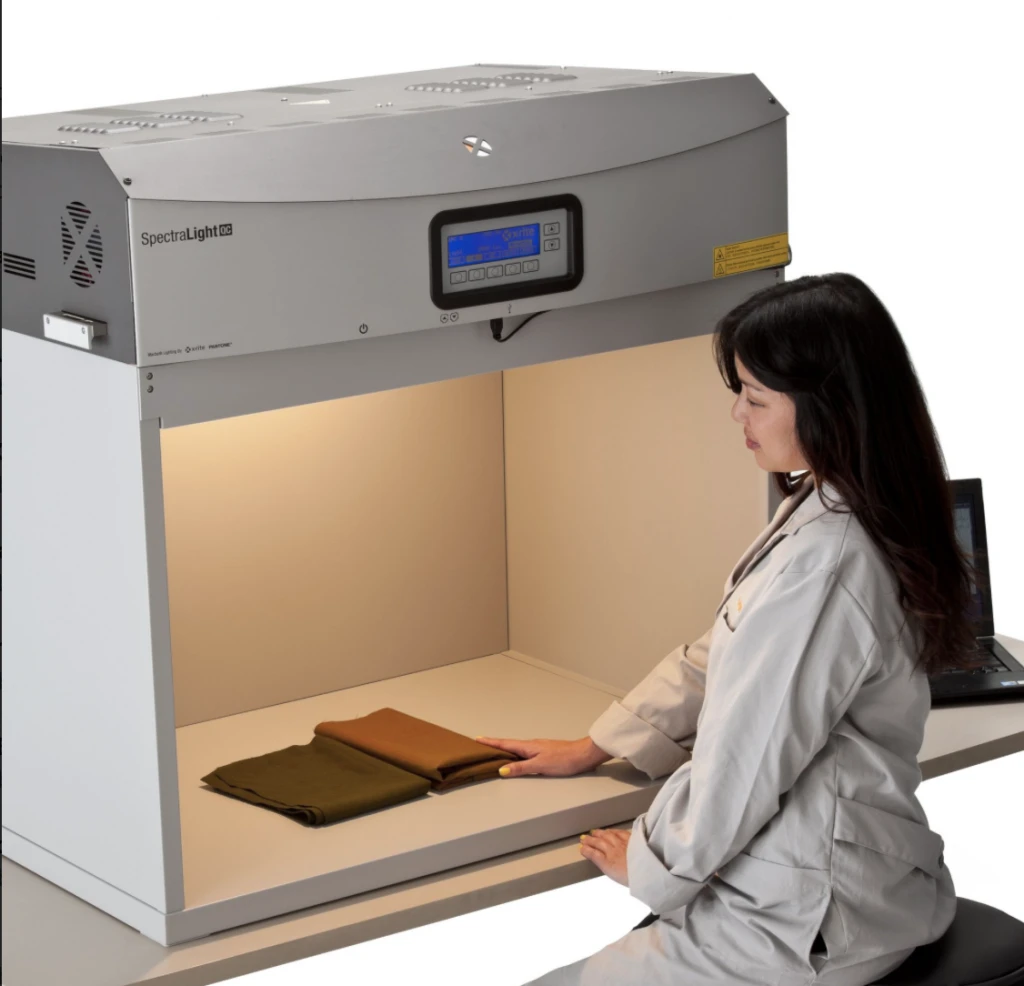 An X-Rite specialist comparing two fabric samples inside a controlled-light viewing booth