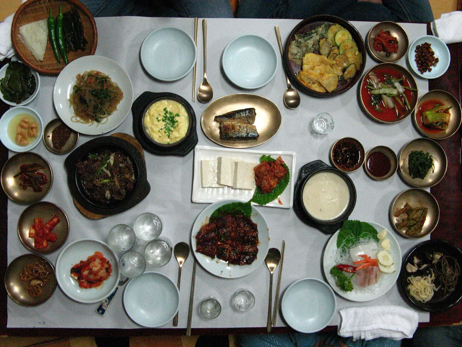 Overhead view of a Korean full-course table with shared dishes and individual place settings