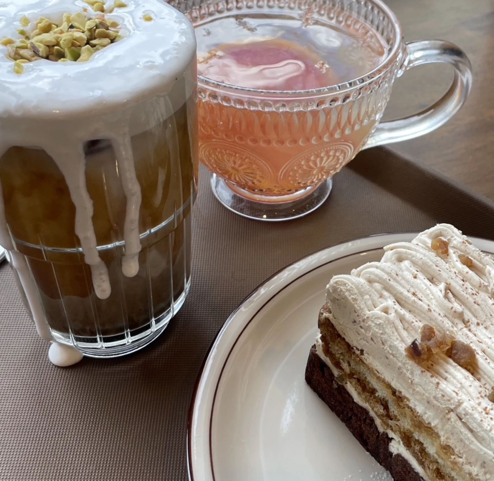 Two cafe drinks and a slice of layered cake served on one tray
