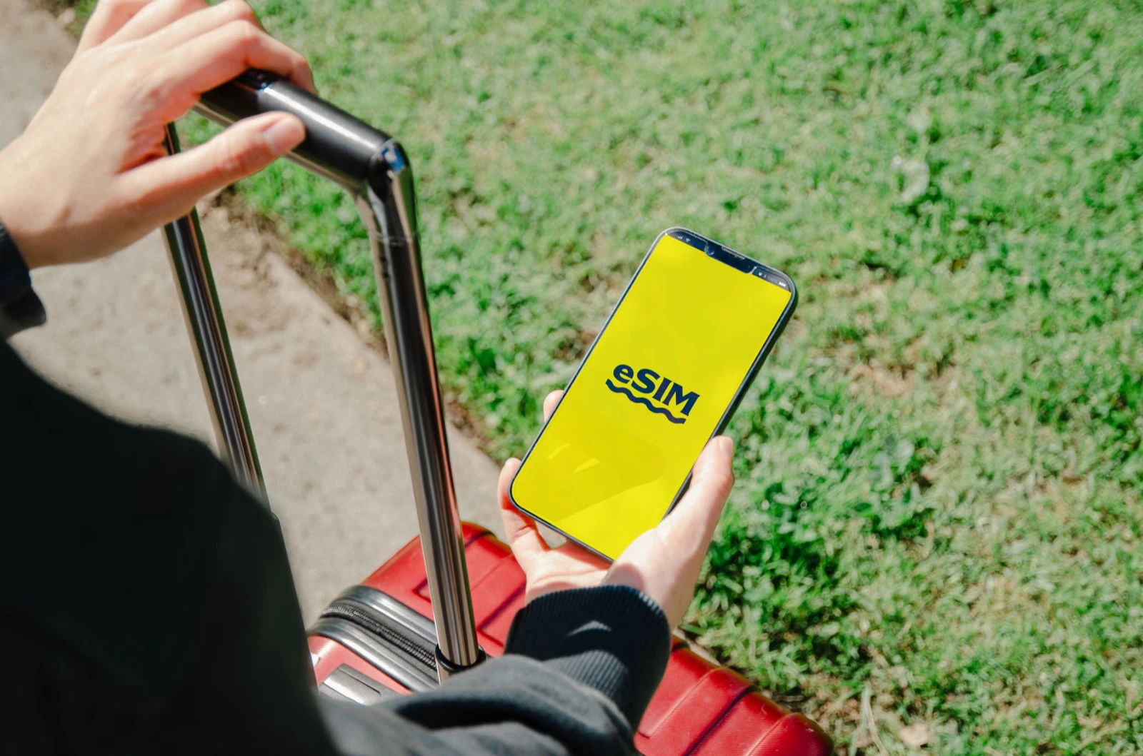 Traveler setting up an eSIM on a smartphone beside a suitcase