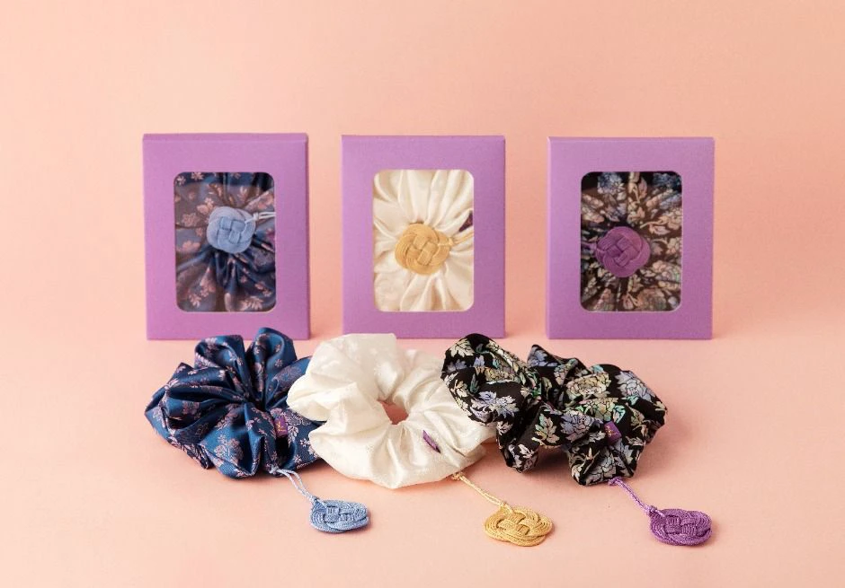 Colorful Korean traditional-knot tassel scrunchies arranged on a pink background
