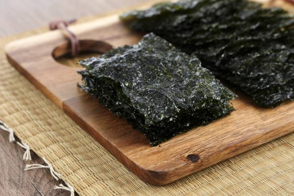 Sheets of roasted Korean gim served on a wooden board