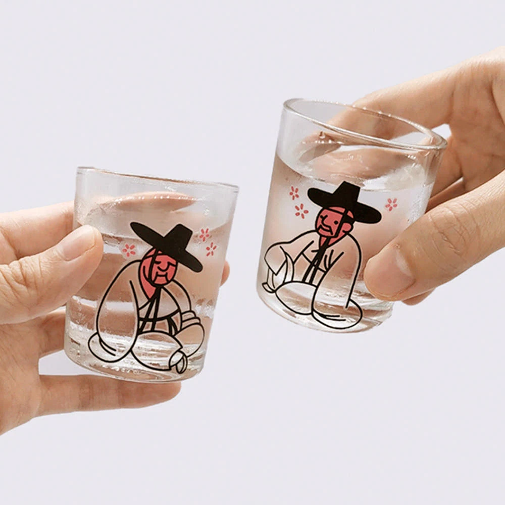 Two hands holding MU:DS Drunken Seonbi cups after the designs turn pink with a cold drink