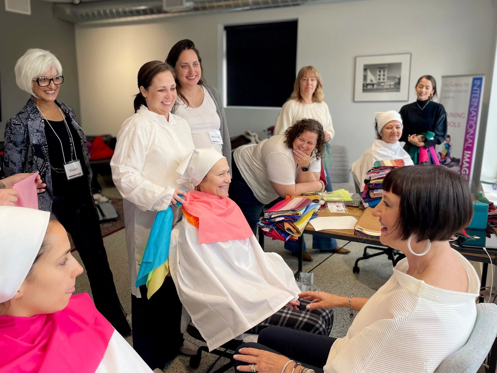 A color-analysis class comparing coral and turquoise drapes on seated clients