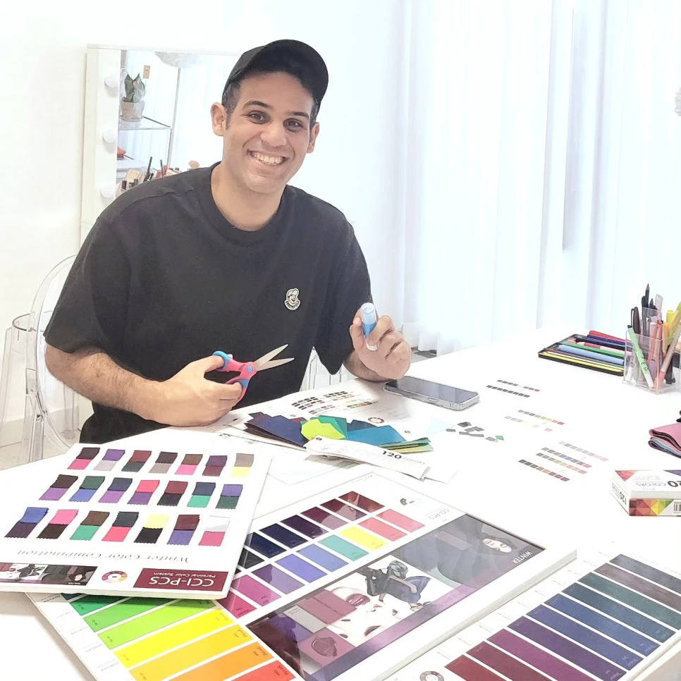 A client at a Korean color studio seated at a table covered with fabric swatches and printed color palettes