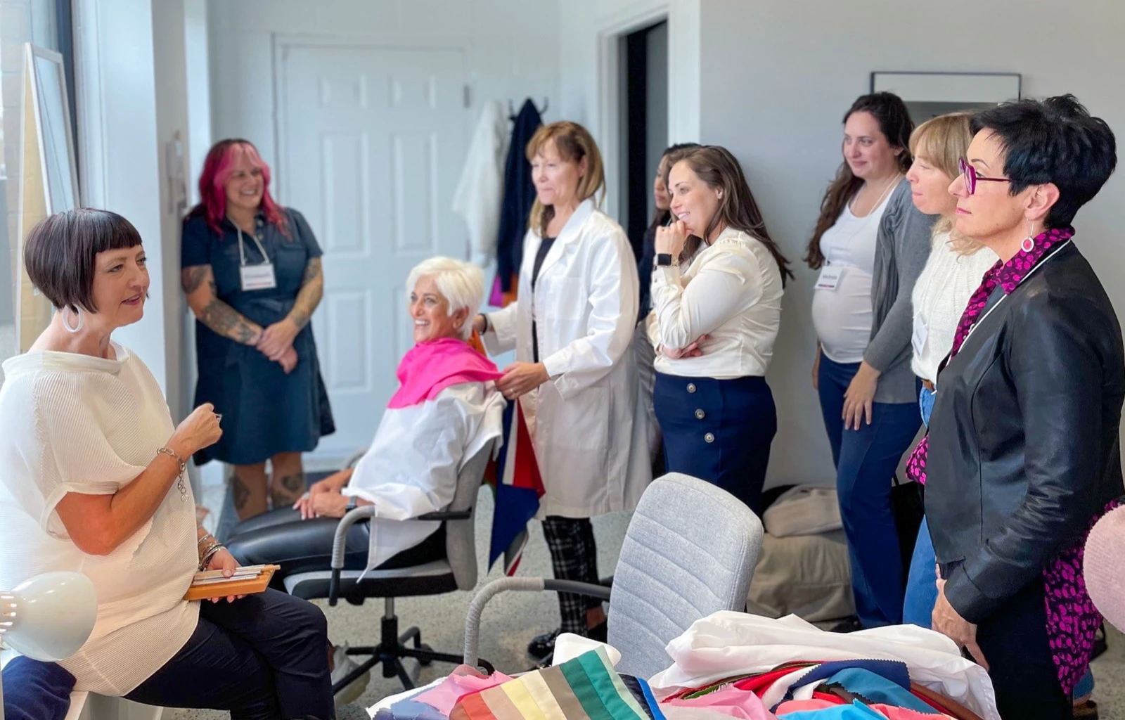 A color-analysis training group observing a client wearing a bright pink drape