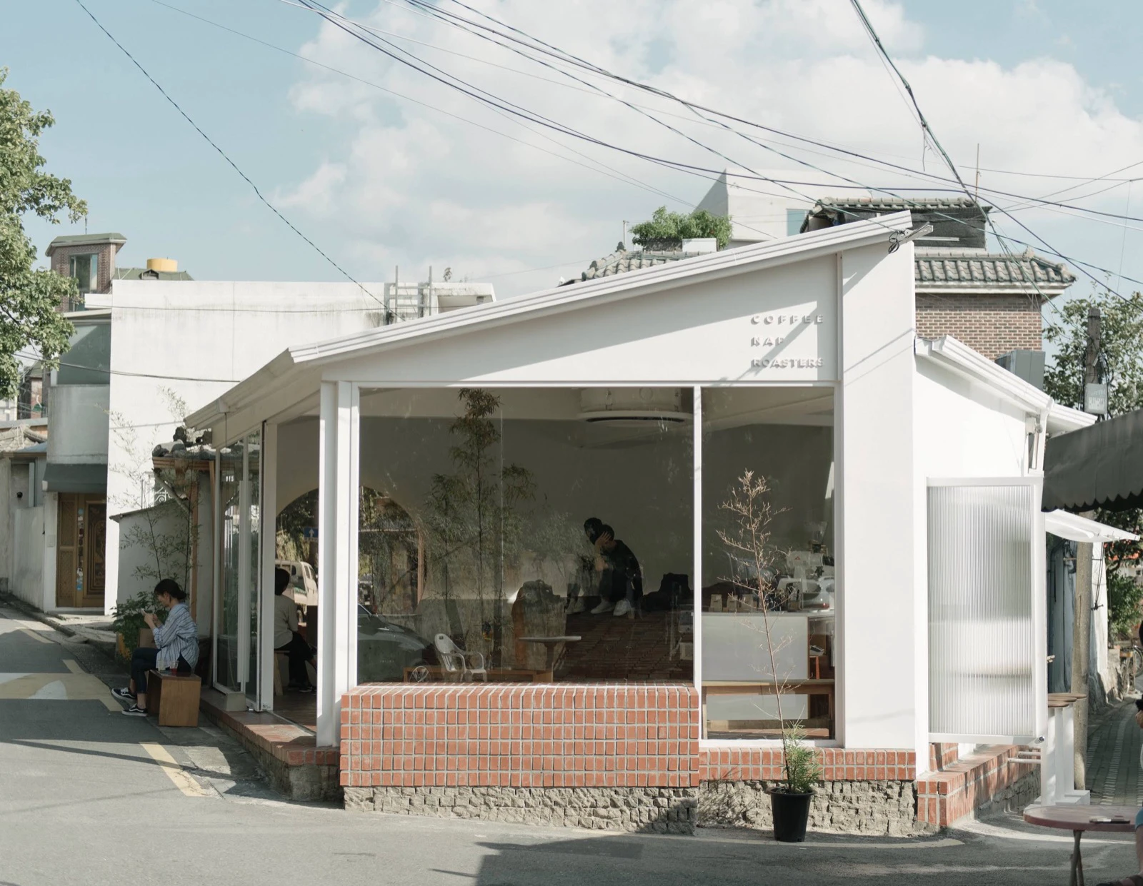 Mặt tiền mái đầu hồi trắng của Coffee Nap Roasters Yeonnam tại góc phố có nắng