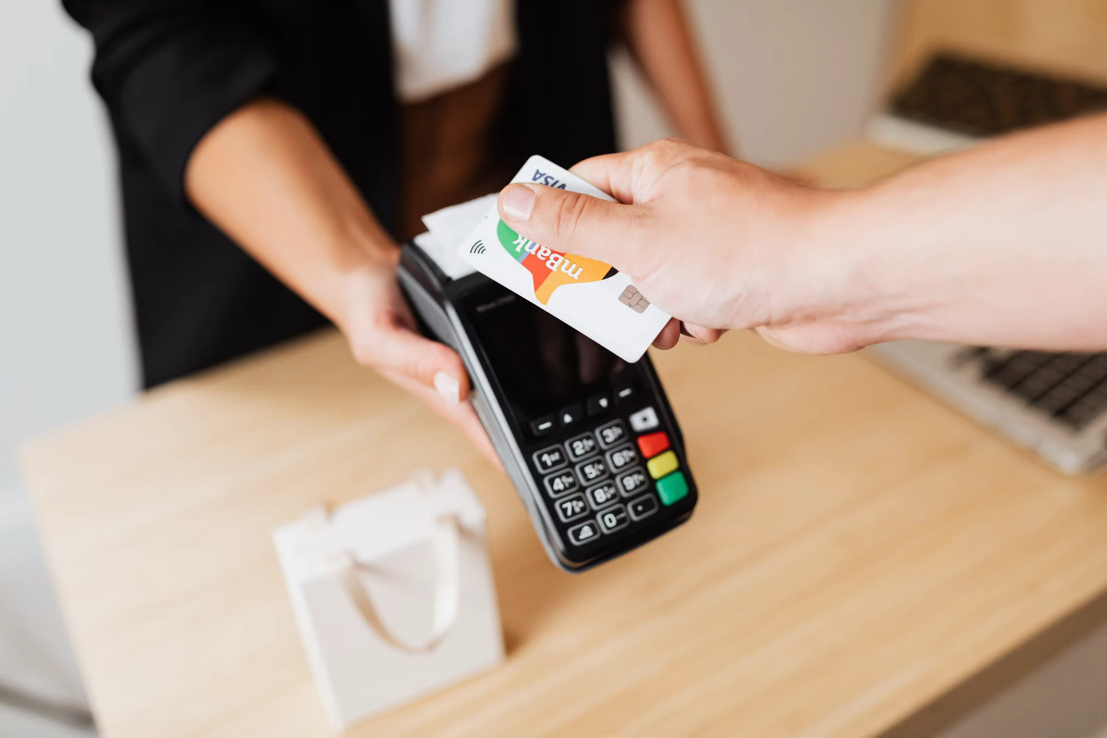 Customer tapping a bank card on a handheld payment terminal