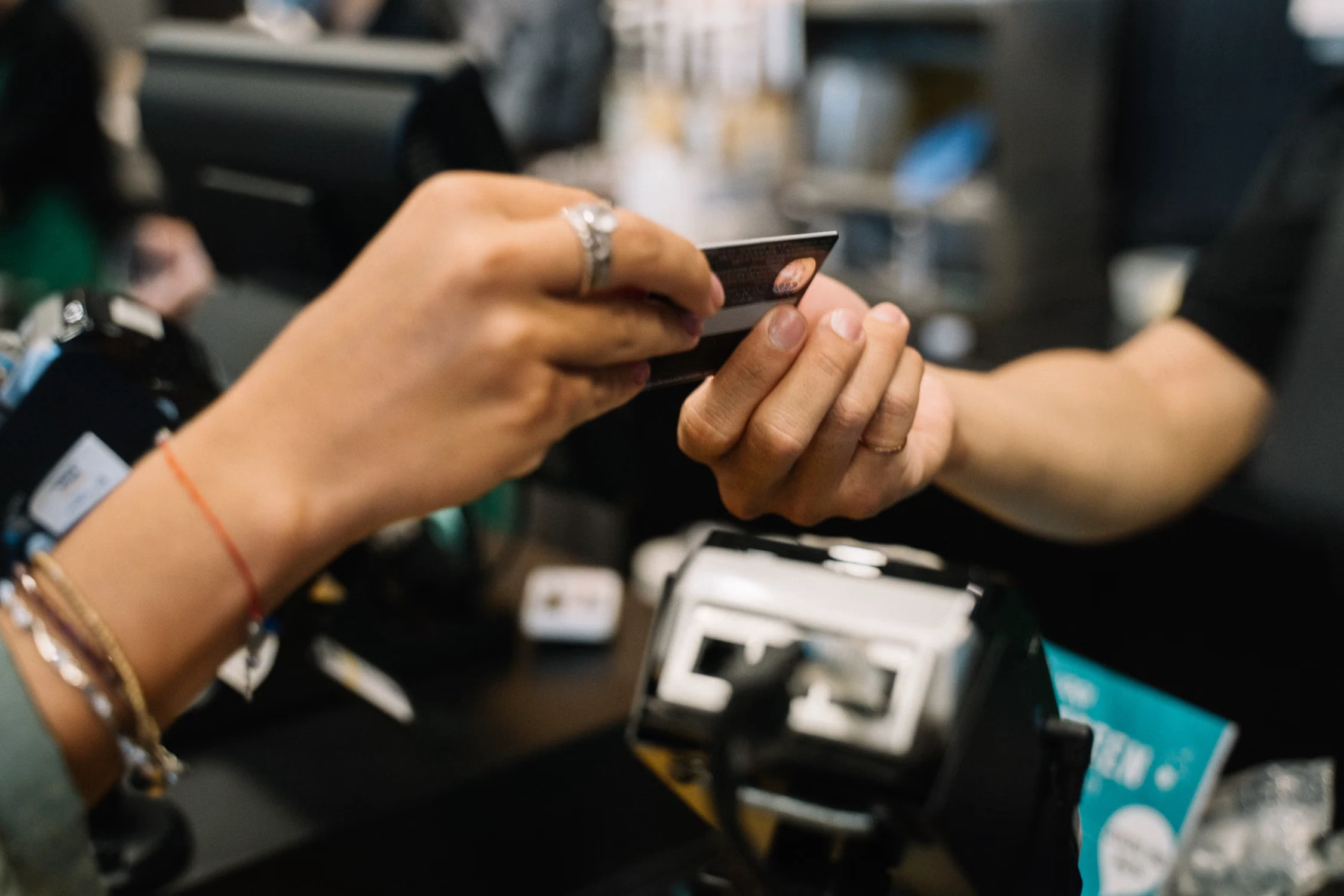 Customer handing a bank card to a staff member at a checkout counter