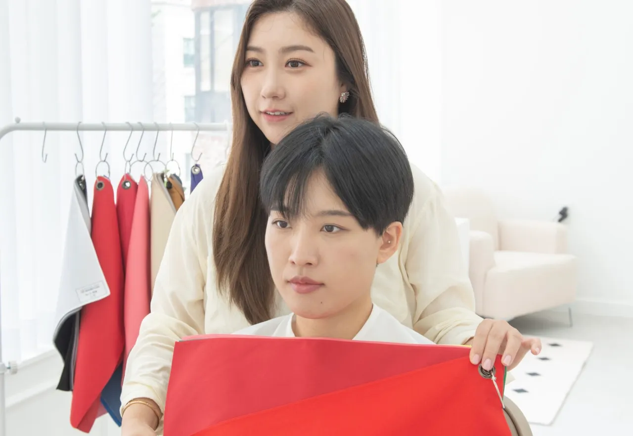 Chuyên viên màu sắc ở Seoul so tấm vải đỏ bên cạnh khách đang ngồi