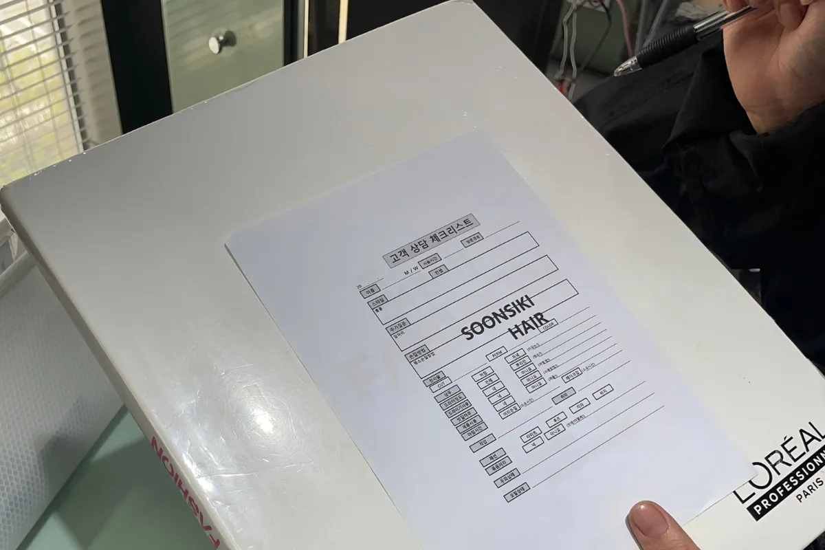 A Seoul hairstylist completing a consultation checklist before a haircut