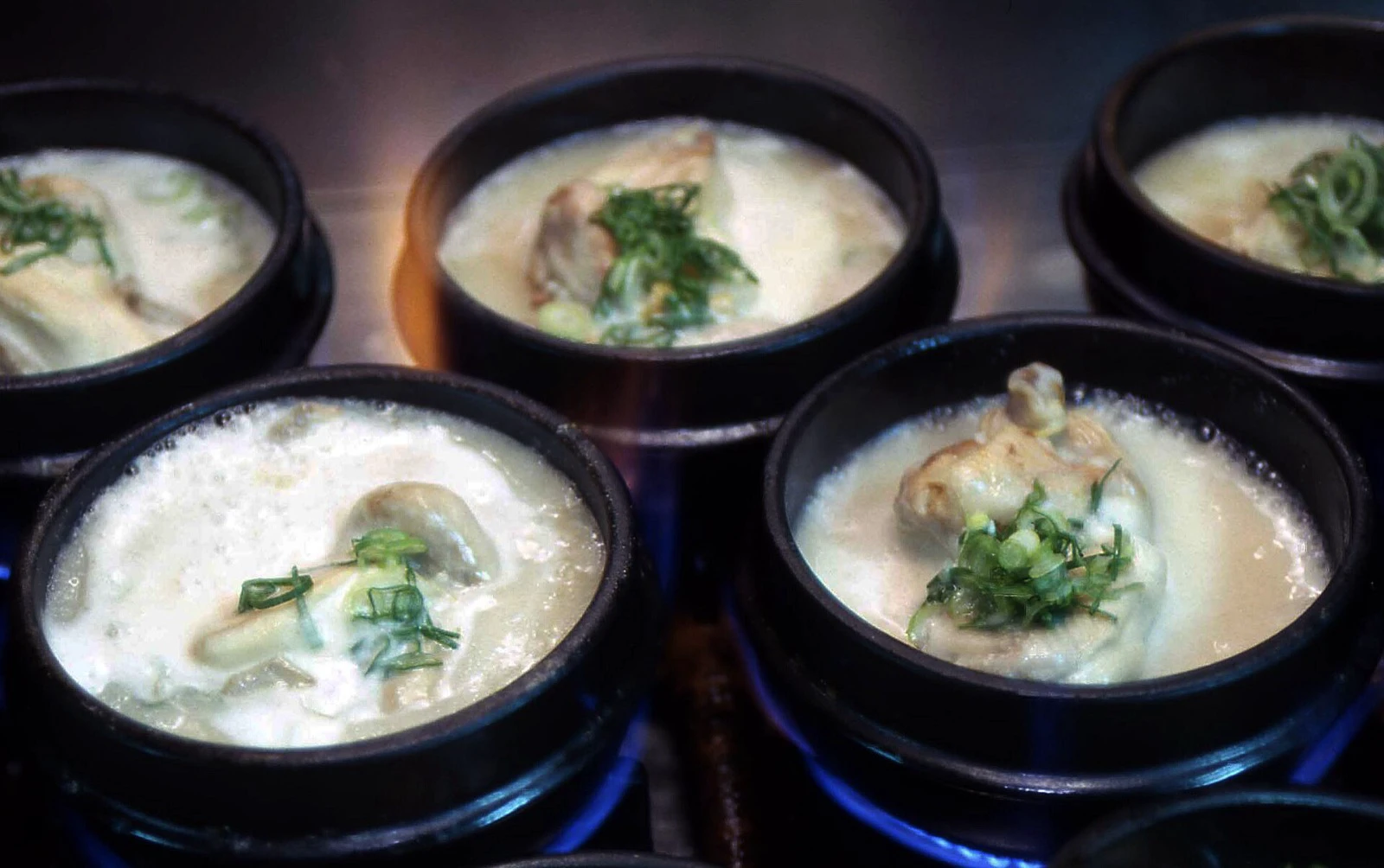Nhiều nồi đá đen đựng samgyetang nước nhạt đang nấu cùng nhau