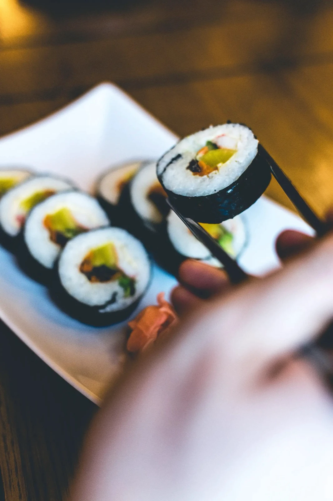 Một lát gimbap Hàn Quốc được gắp bằng đũa trên đĩa