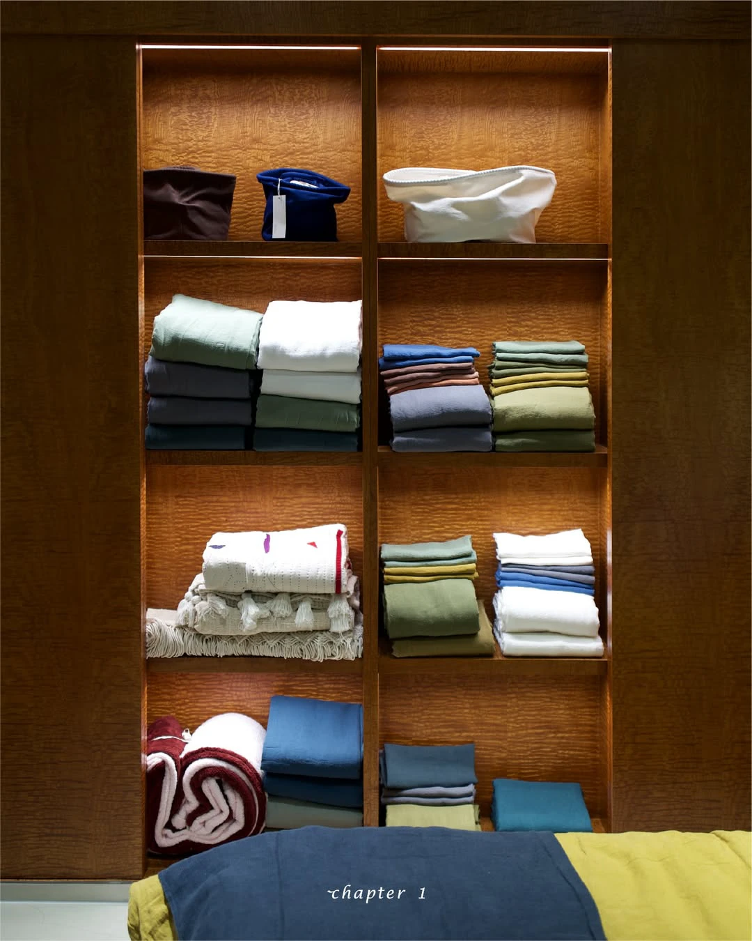 Warm wood shelving at Chapter 1 Hannam displaying folded textiles and small design objects