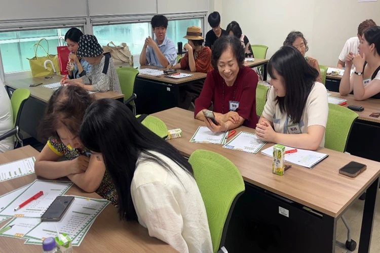 Younger and older women working together with smartphones at a Seoul community workshop