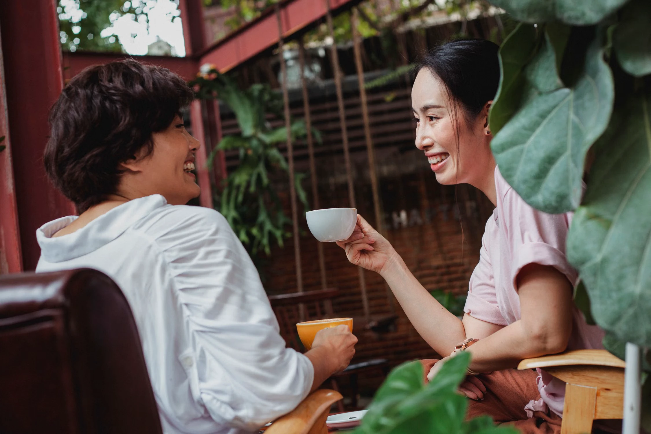 Two women of different ages smiling over coffee during a relaxed conversation