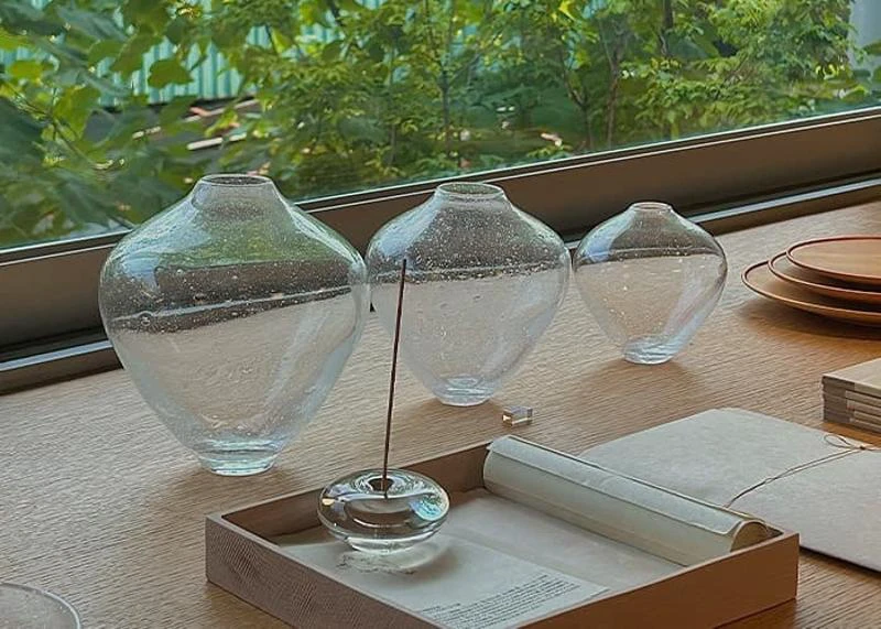 Handcrafted glass vessels displayed by a window at MONOHA HANNAM