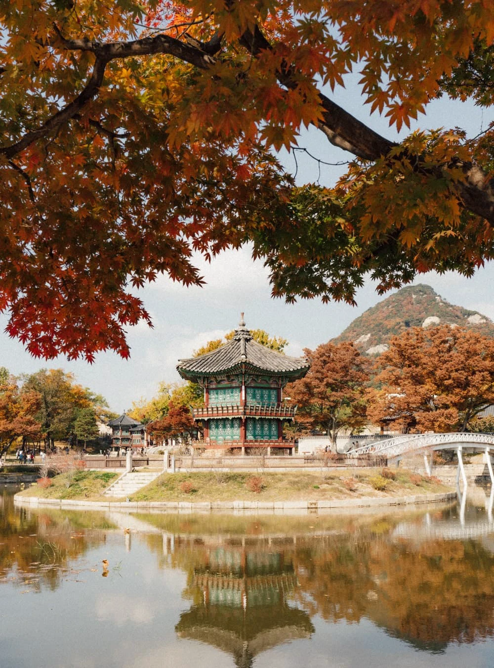 Red and orange maple leaves framing Hyangwonjeong Pavilion and its pond reflection at Gyeongbokgung Palace