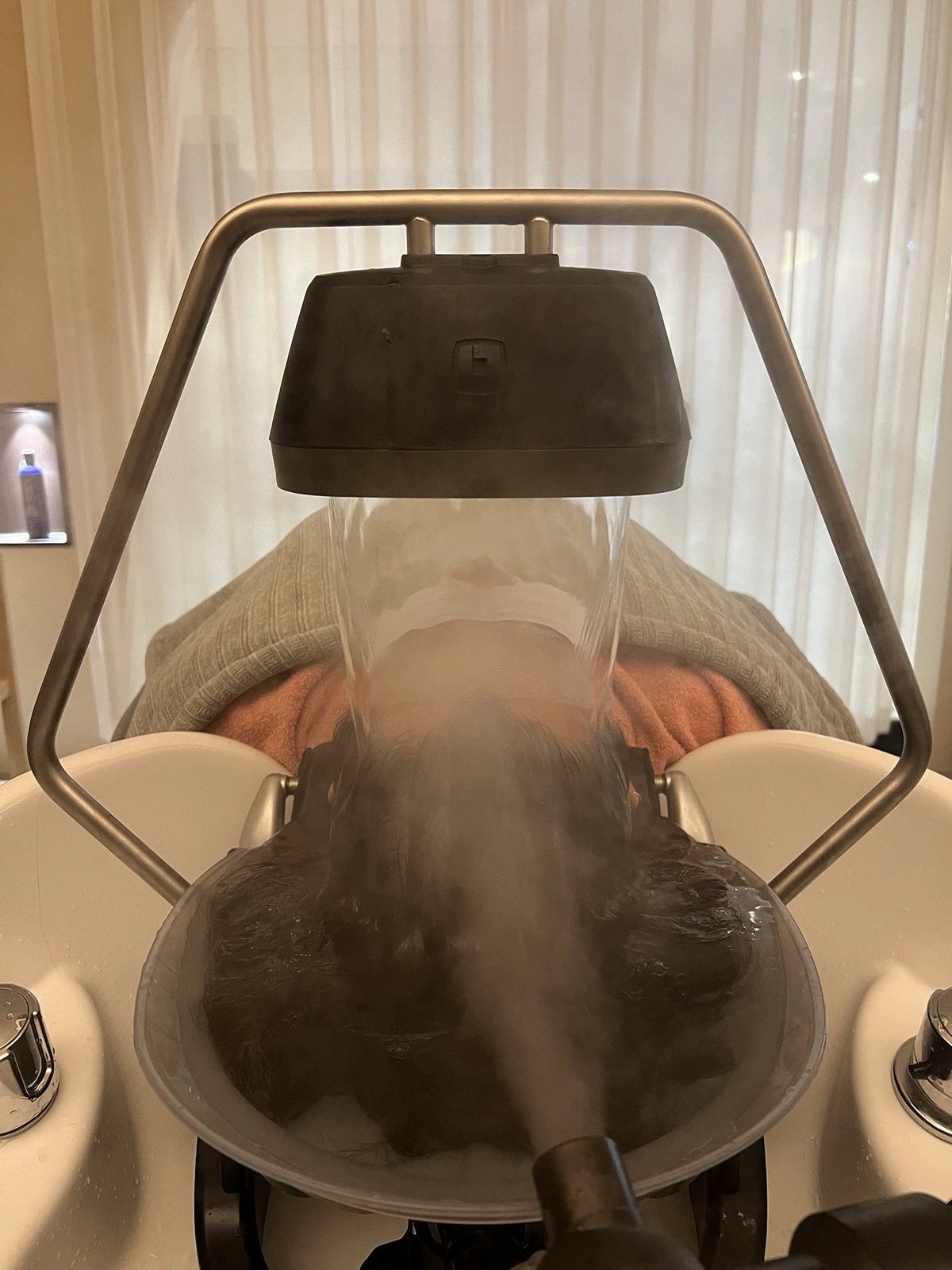 Traveler reclining beneath a waterfall-style head-spa rinse in a Seoul salon
