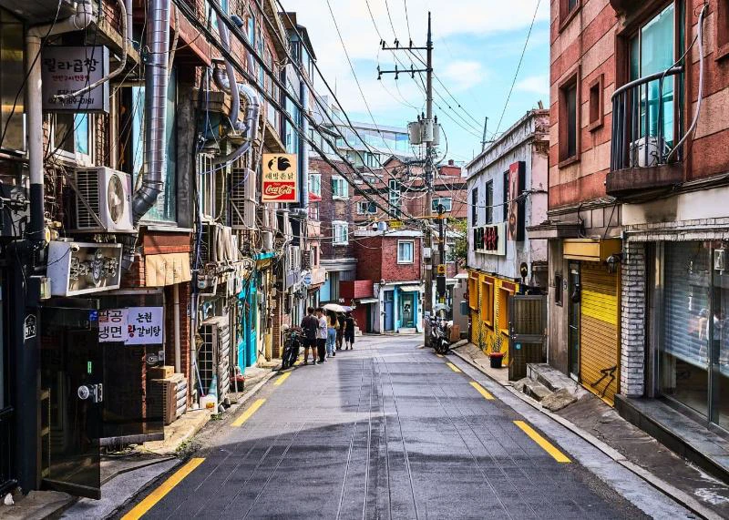 Narrow Haebangchon street descending between brick homes and small shops