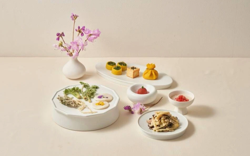 Small spring temple-food dishes arranged with flowers on pale ceramic plates at Balwoo Gongyang