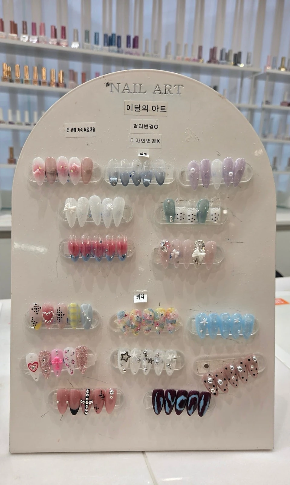 A monthly nail-art display board with bows, pearls, rhinestones, florals and blue designs