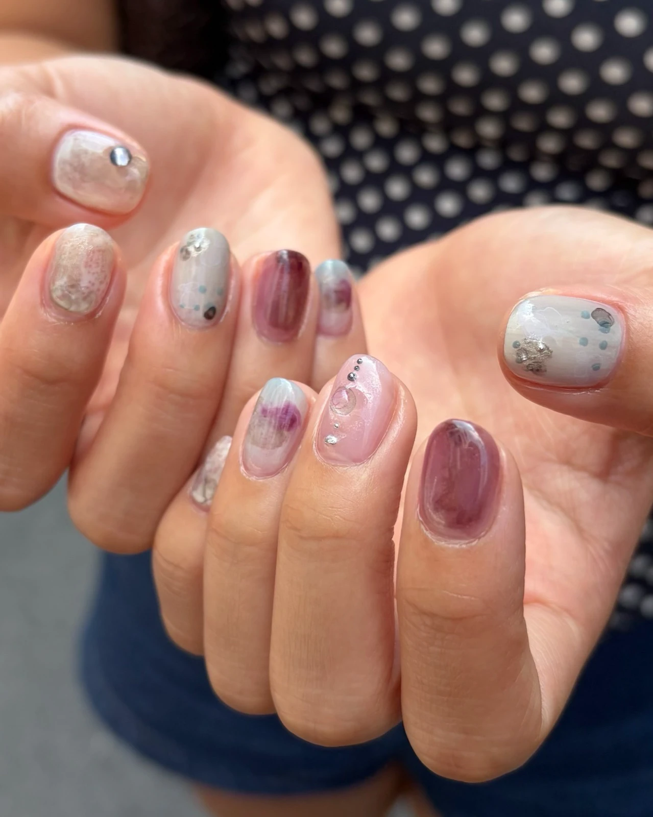 Short Korean gel nails in plum, silver and pale blue with small metallic accents