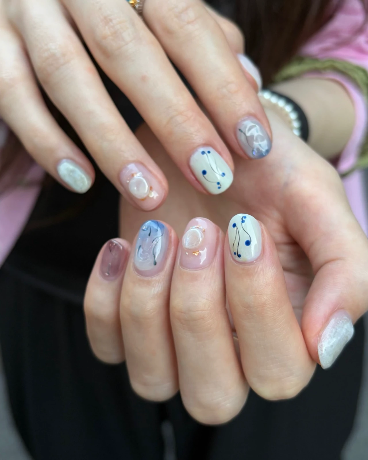 Short Korean gel nails with blue lines, white swirls and translucent raised accents