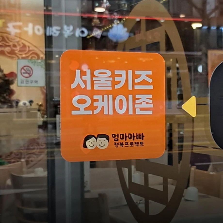 Orange Seoul Kids OK Zone sticker displayed on a restaurant entrance