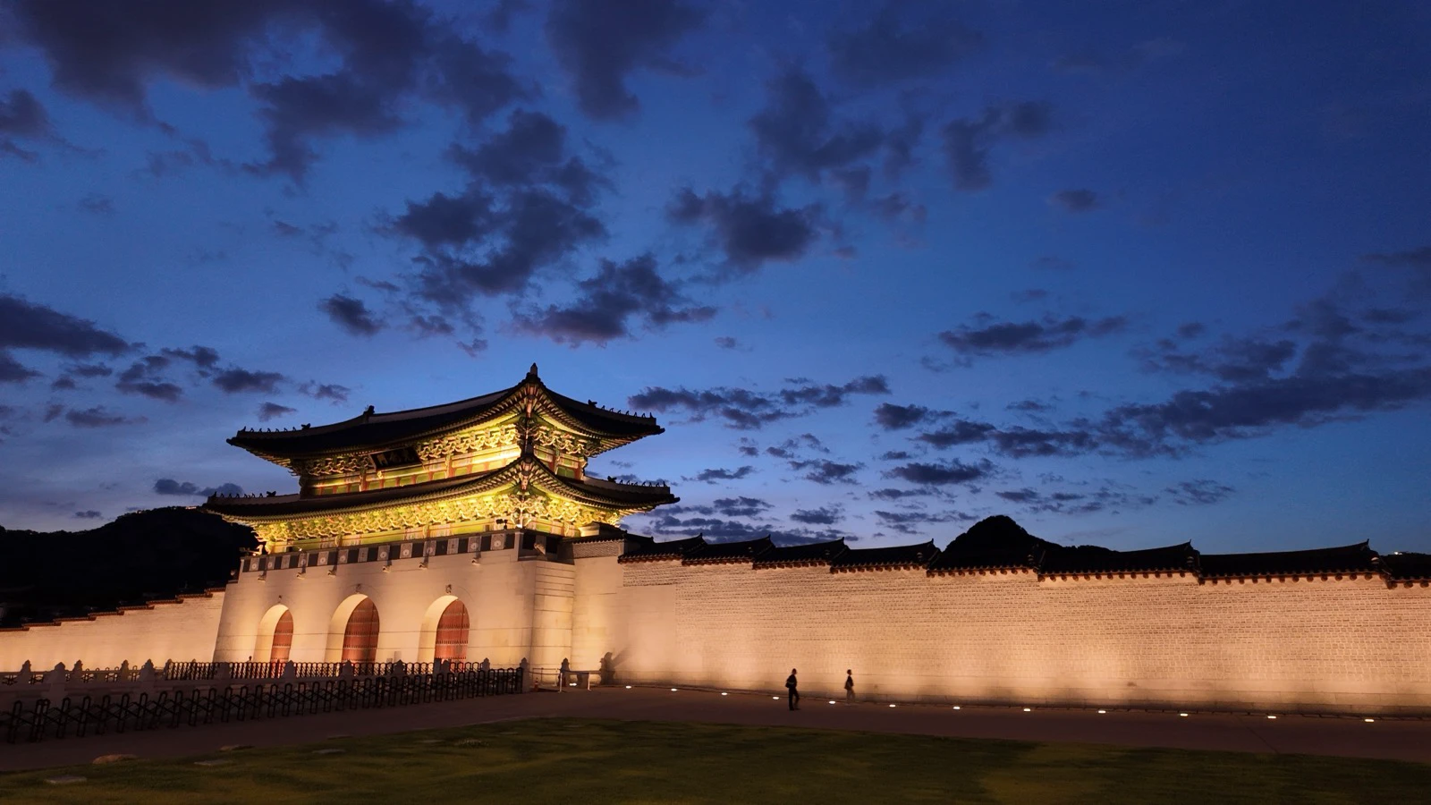 Gwanghwamun Gate illuminated under a blue evening sky outside Gyeongbokgung Palace