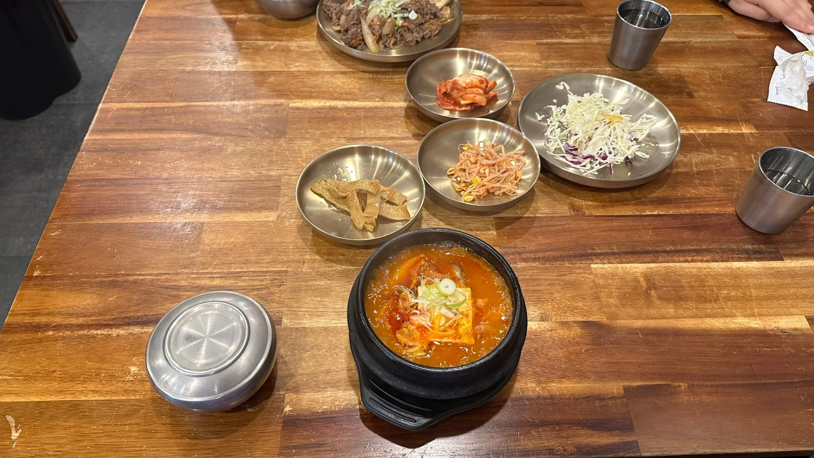 Halal Korean stew, beef bulgogi and side dishes arranged on a wooden table at Eid in Itaewon