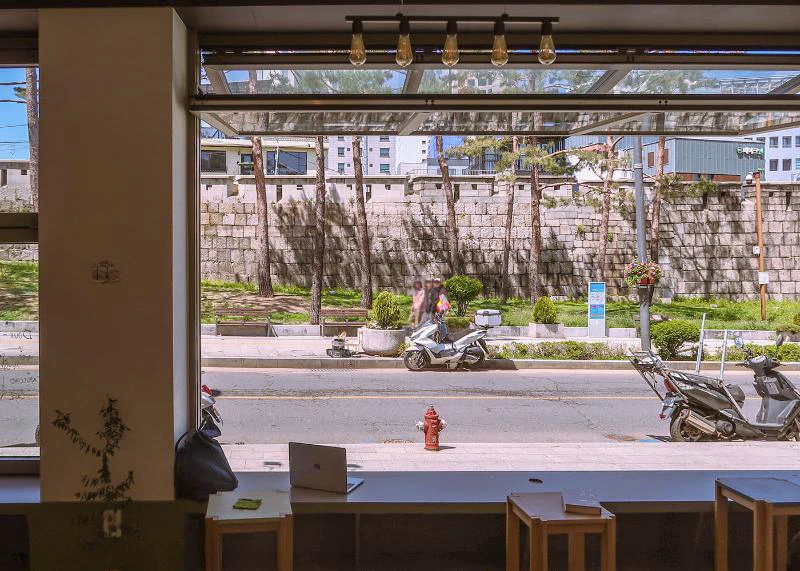Café window and empty counter seats framing the Seoul City Wall outside