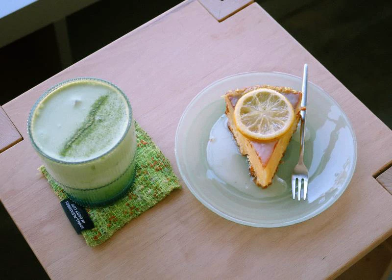 Matcha drink and lemon dessert photographed on a café table without other customers in frame