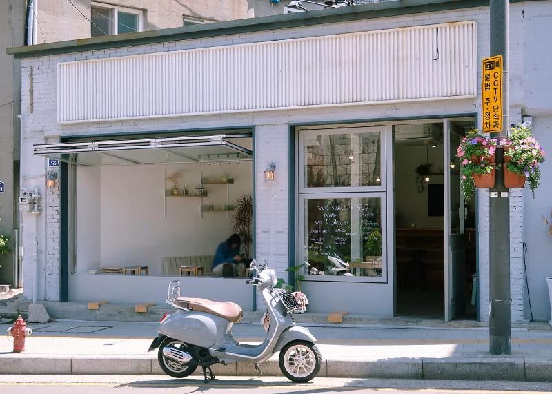 White Seoul café storefront photographed from across the street with the entrance unobstructed