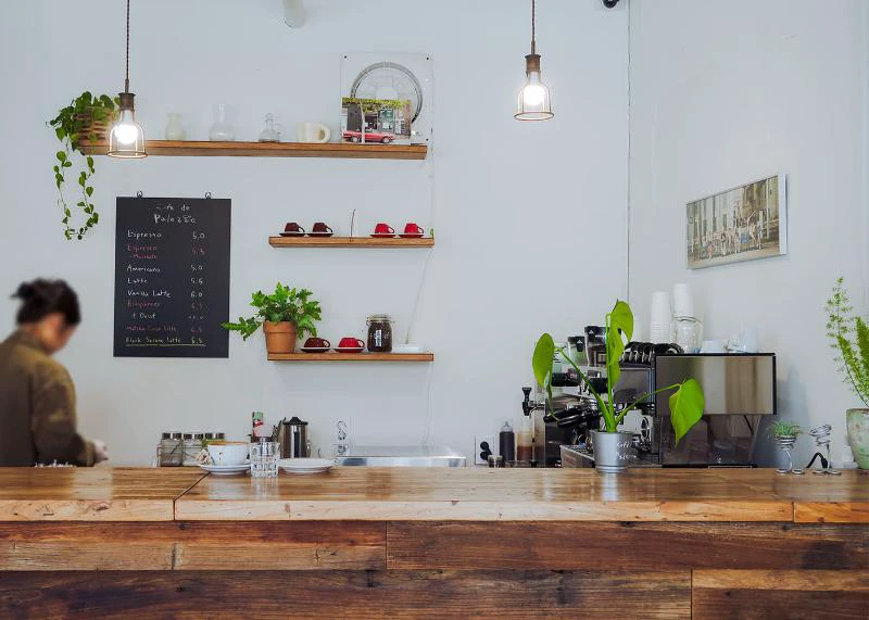 Wide café counter view focused on menu boards and equipment while the worker remains unidentifiable