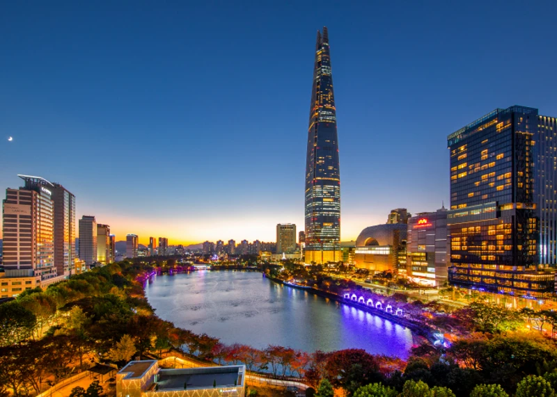 Lotte World Tower rising beyond Seokchon Lake at blue-hour twilight