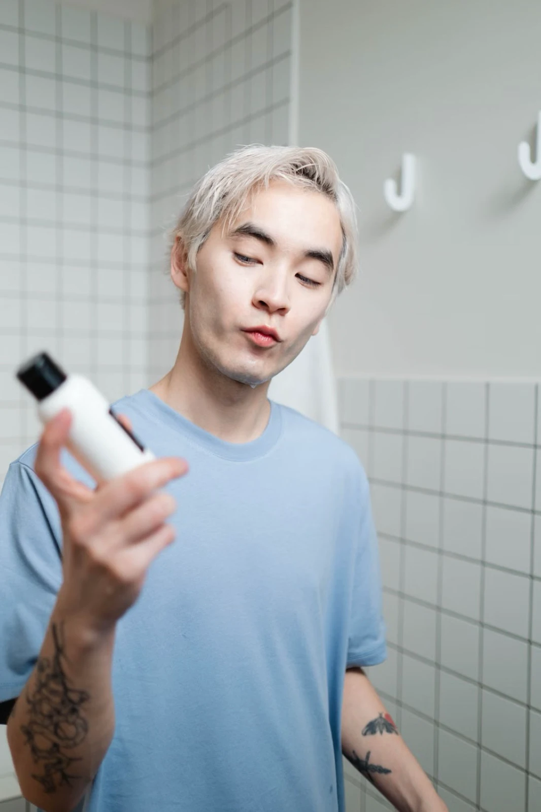 Một người đàn ông đọc nhãn chai chăm sóc da trong phòng tắm