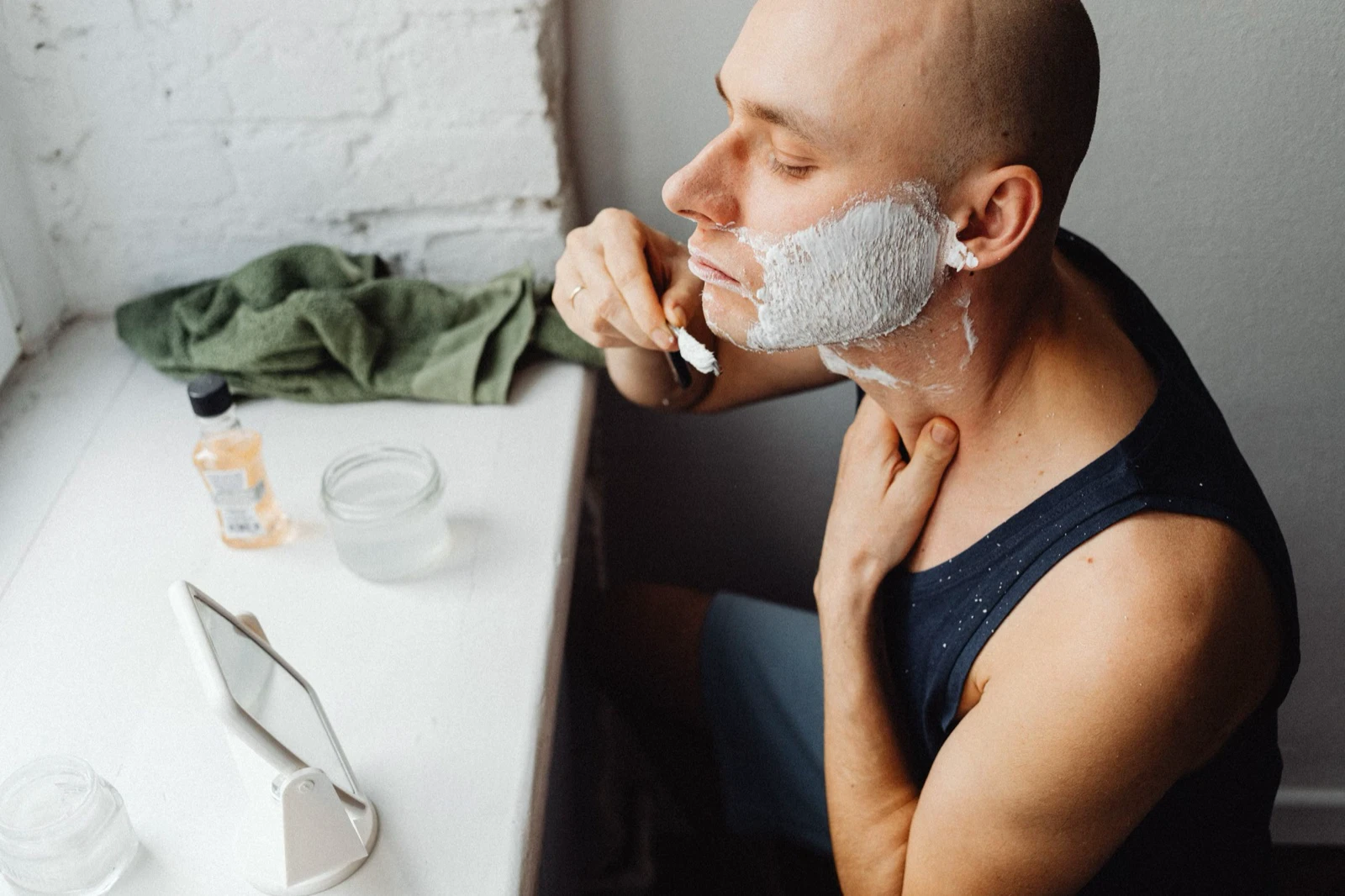 Một người đàn ông cạo râu sau khi thoa kem cạo râu