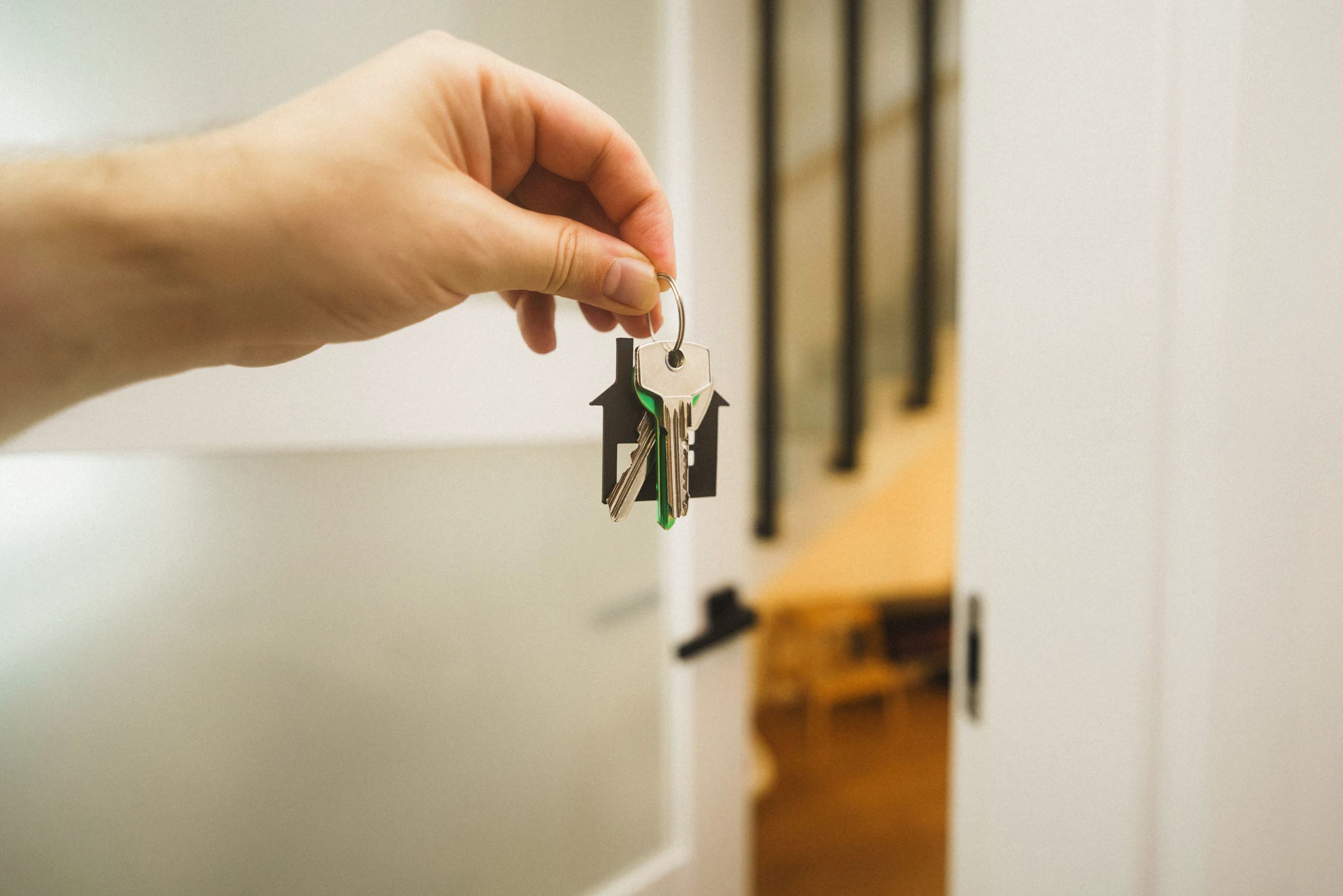 A hand holding house keys inside a bright modern home