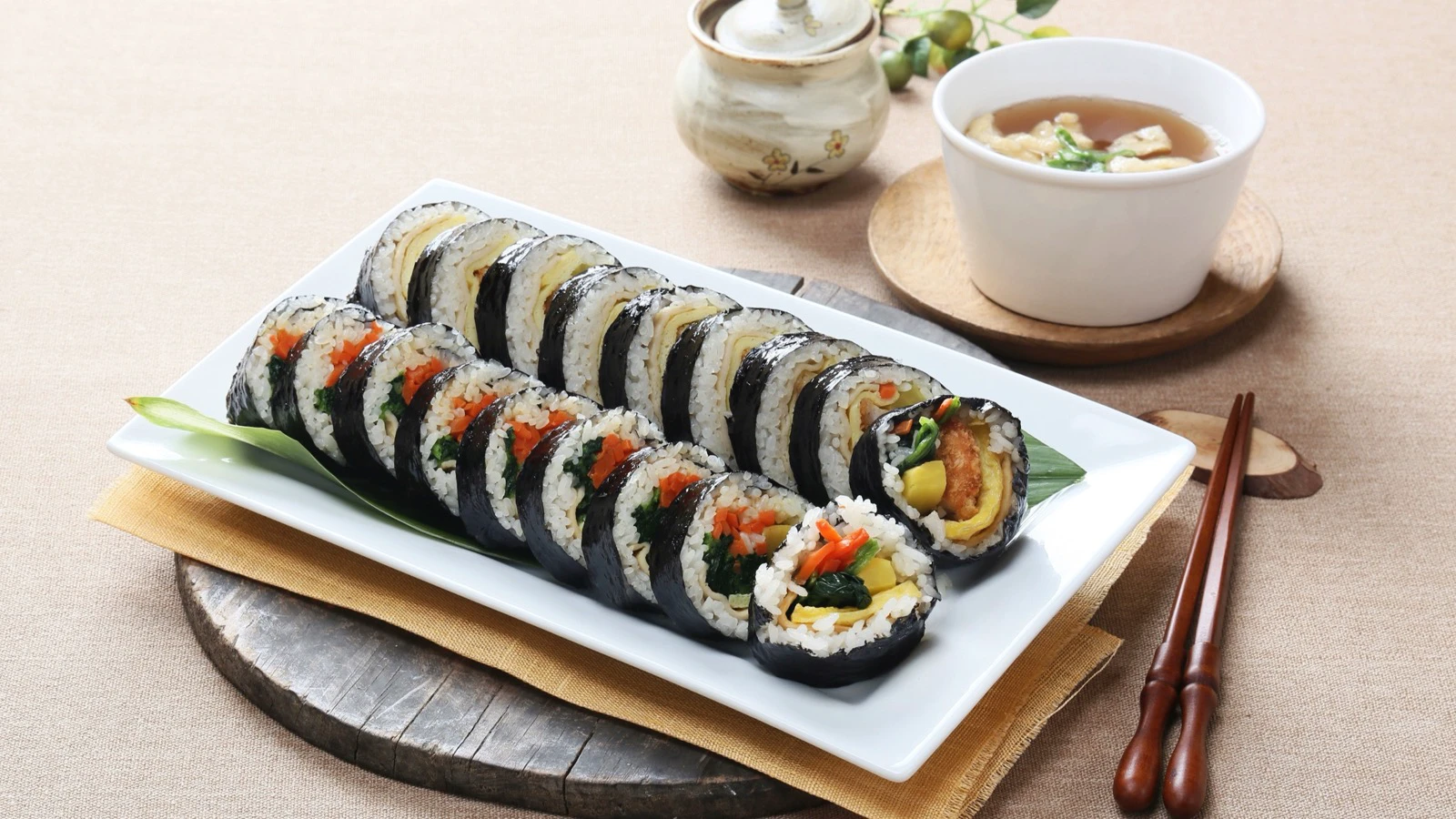 Fresh sliced gimbap rolls with soup and chopsticks, ready for a quick Korean breakfast