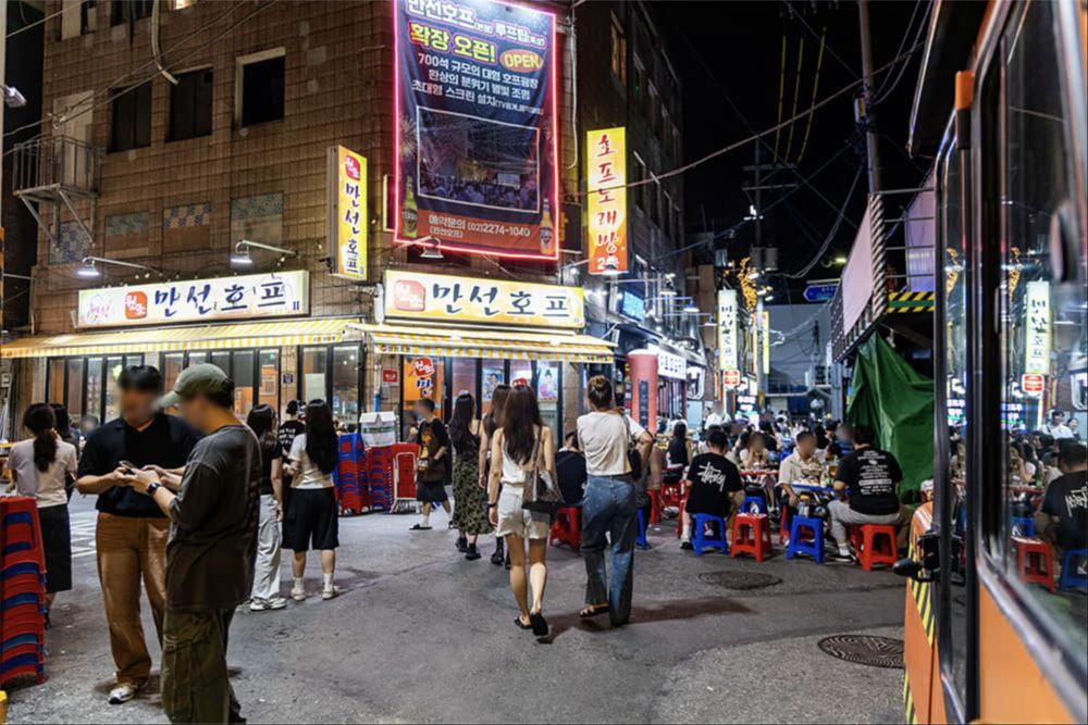 People walking and dining in a narrow Euljiro alley under neon signs at night