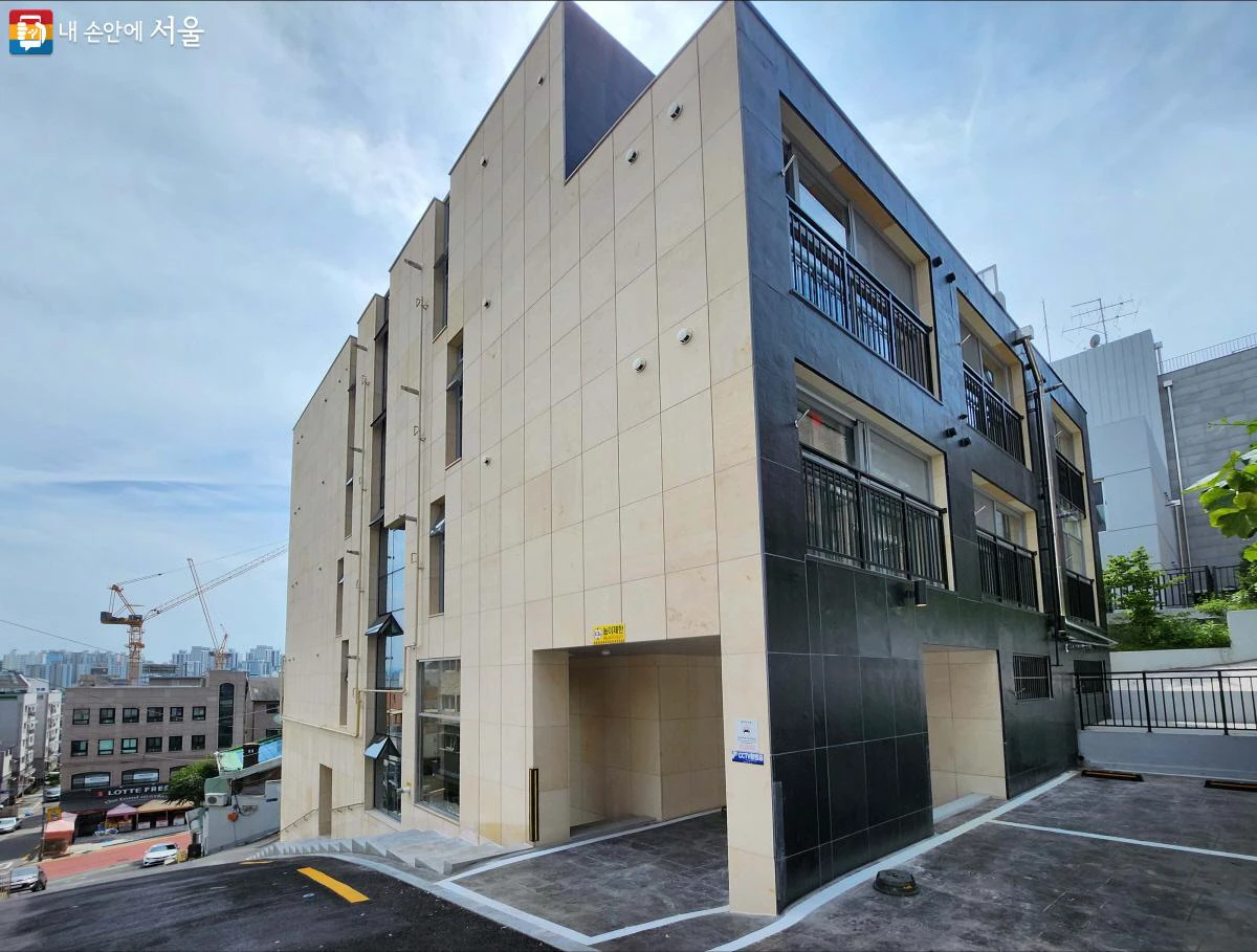 A modern five-floor low-rise multi-unit residential building on a sloping Seoul street