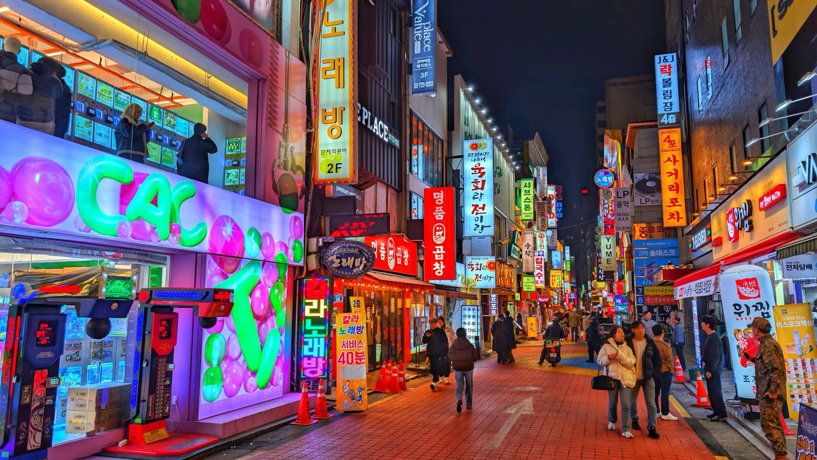 Neon restaurant and entertainment signs above a busy Seoul street at night