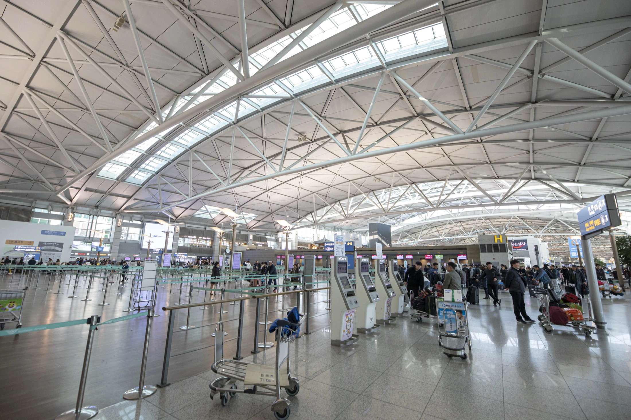 Wide Incheon Airport Terminal 1 departure hall with check-in islands beneath a curved steel roof