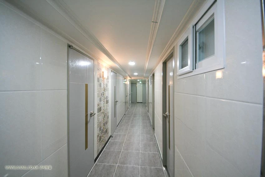 Bright modern goshiwon corridor lined with individual room doors and exterior windows