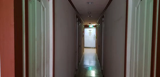 Narrow dim corridor with closely spaced doors inside an older Seoul goshiwon